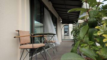 Ein kleiner Außenbereich mit Tisch und Stühlen, eine überdachte Terrasse und Kübelpflanzen.