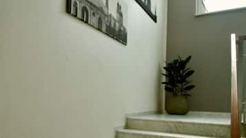 A staircase with marble steps, a potted plant on the landing, and two black-and-white photographs on the wall.