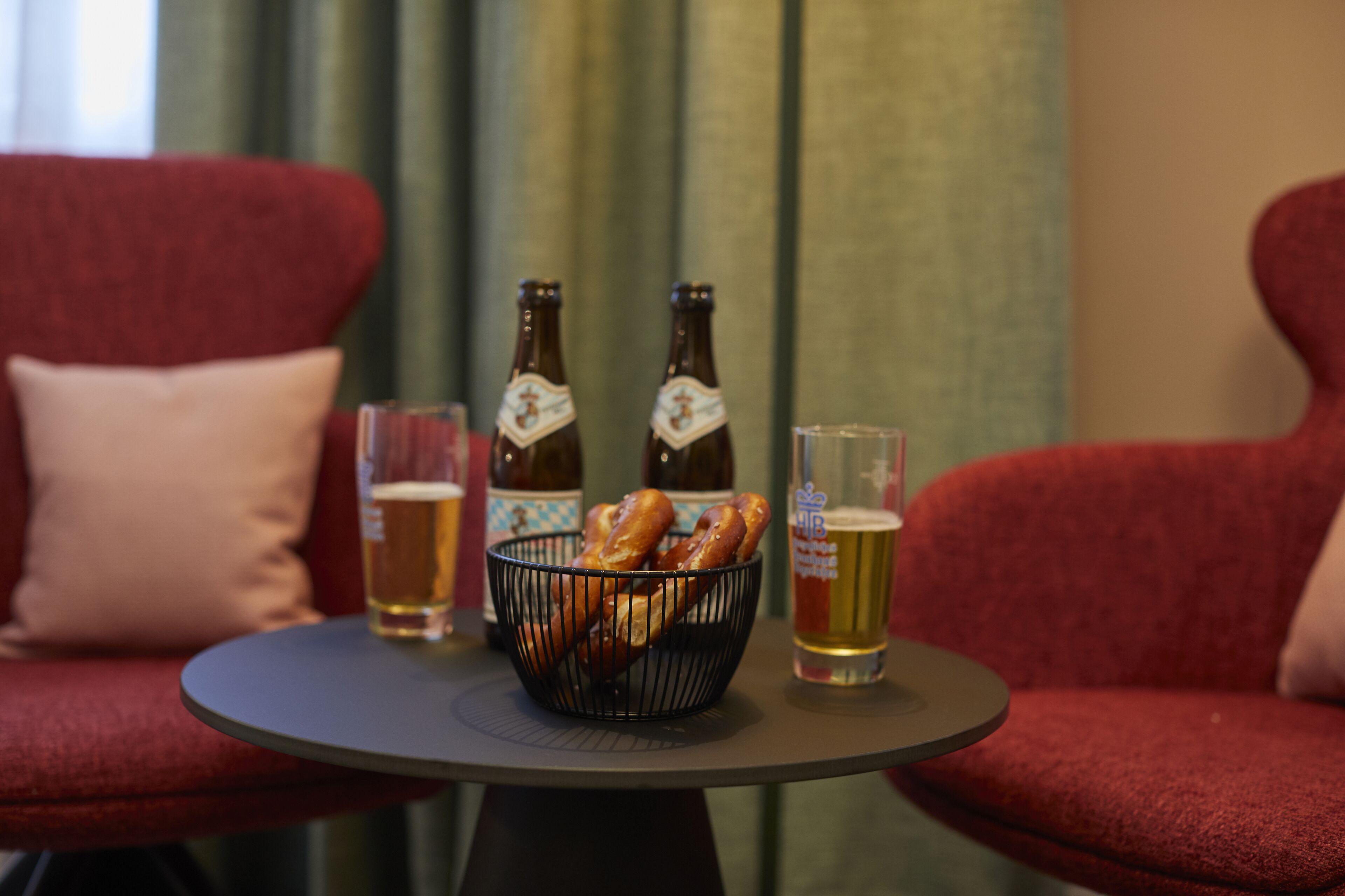 Ein Tisch mit zwei Bierflaschen, einem Bierglas und einer Brezelkorb.