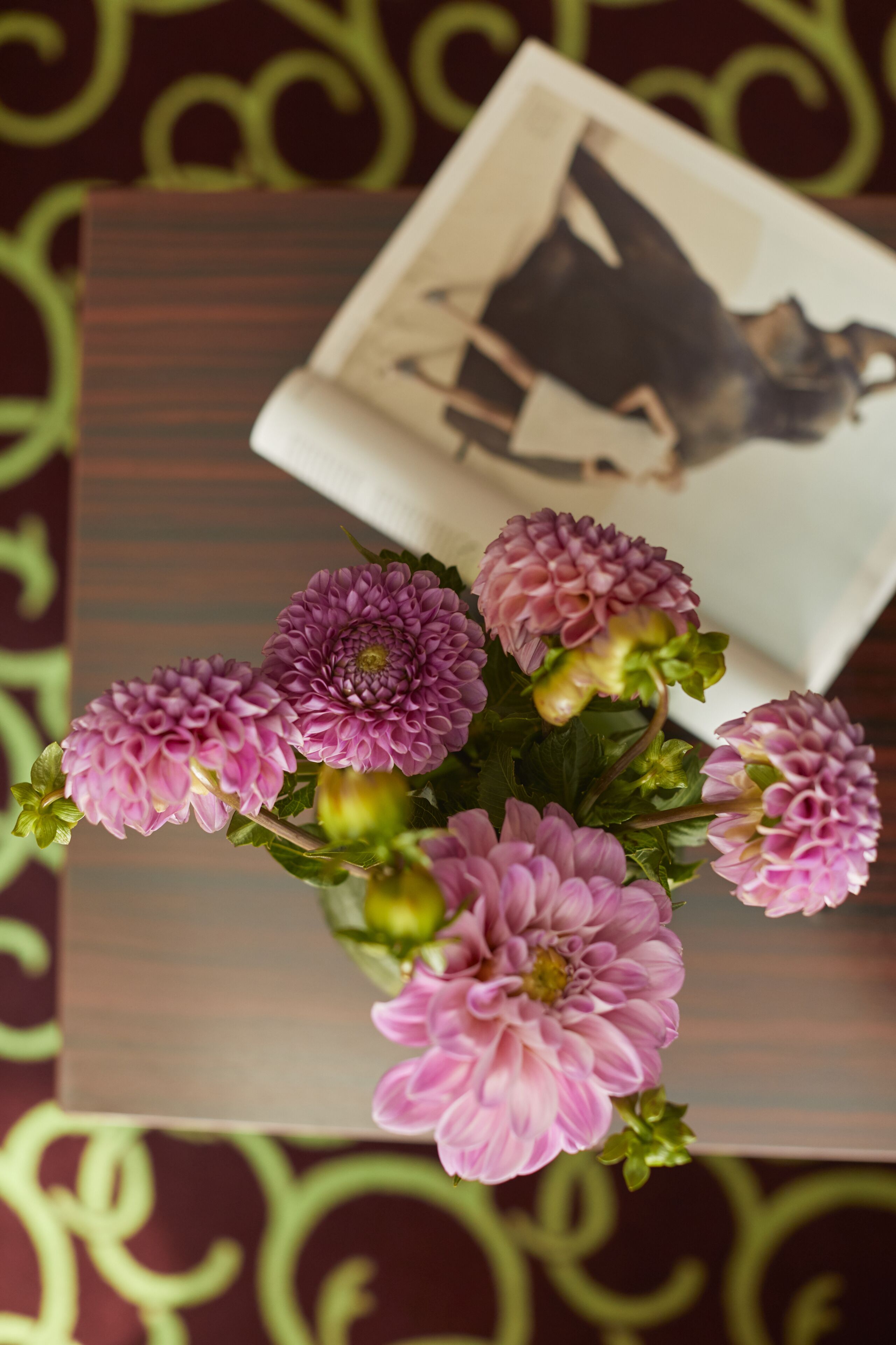 Una mesa con un florero de flores rosas y un cuadro enmarcado.