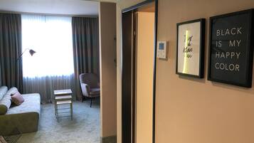 A hotel room with a bed, a chair, a small table, and a wall with framed inspirational quotes.