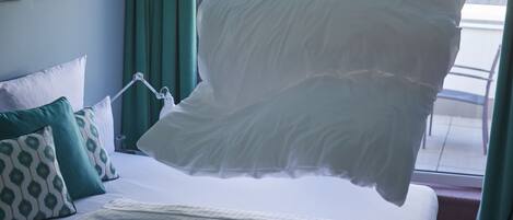 Una cama bien hecha con sábanas blancas y un cojín decorativo.