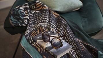 A book titled 'ACH' and sunglasses on a patterned fabric.