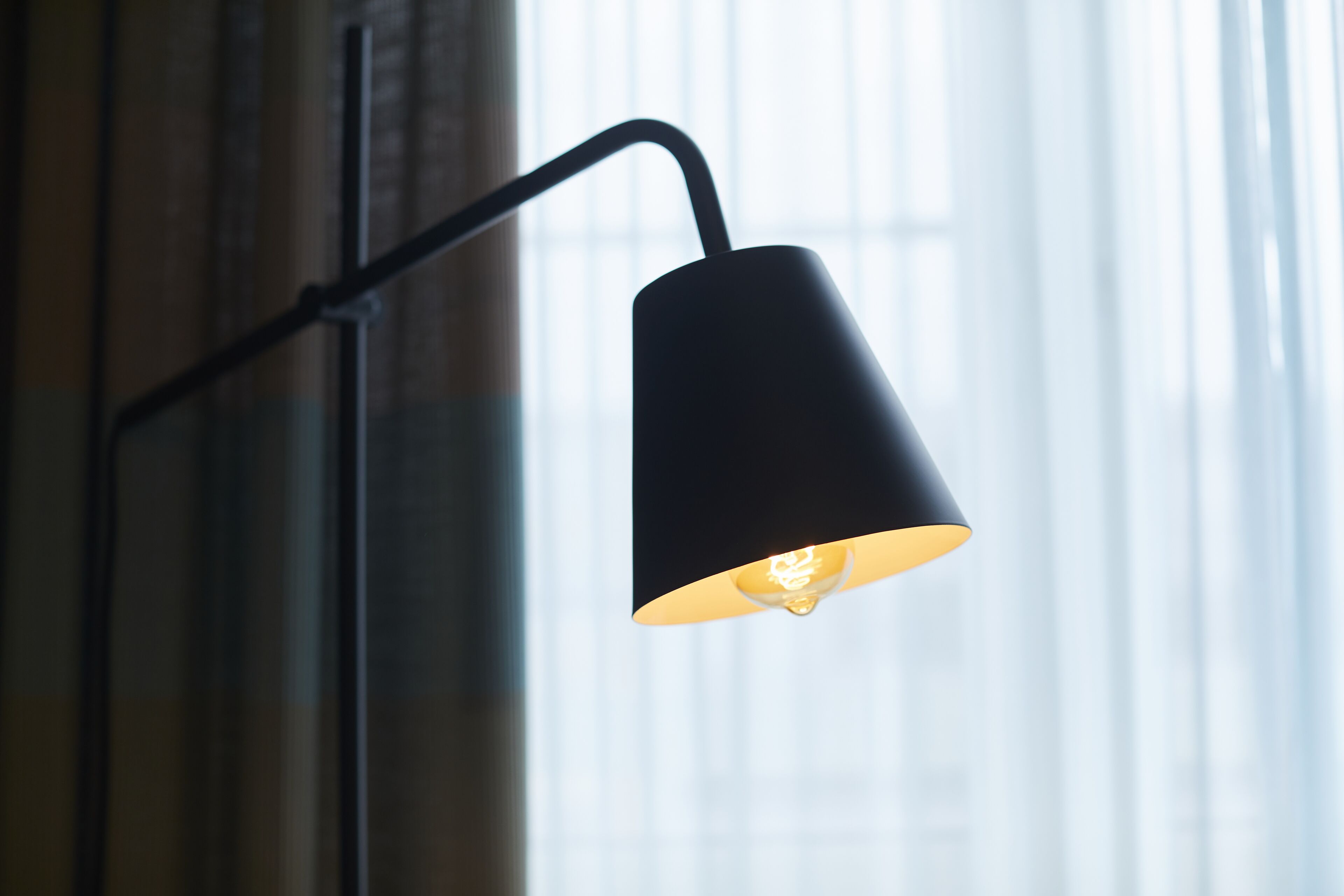 A black pendant lamp with a single bulb, hanging from a black metal bracket.