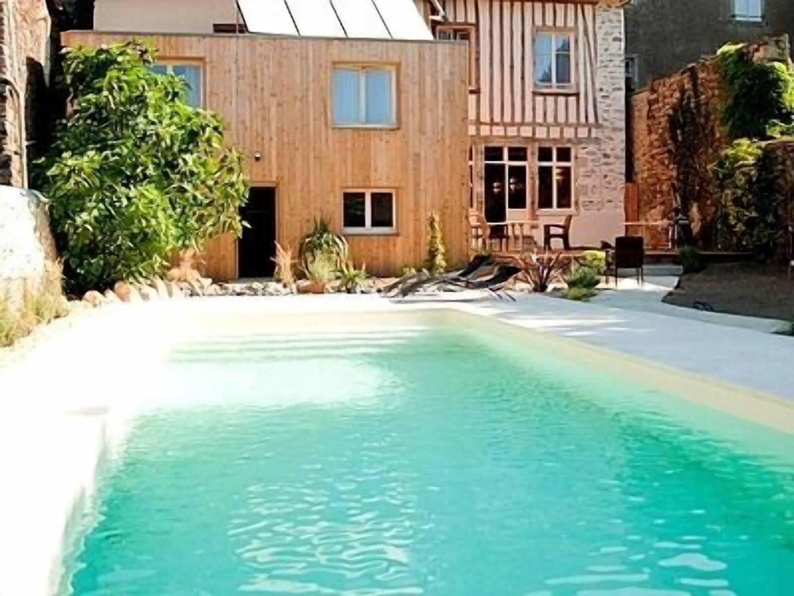 Una piscina con agua cristalina, rodeada por una cubierta de madera y muros de piedra.