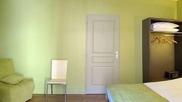 A room with a bed, a chair, a wardrobe, and a door.