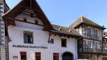 Un edificio con un letrero que dice "AUBERGE DUPUYTREN" y un coche estacionado adelante.