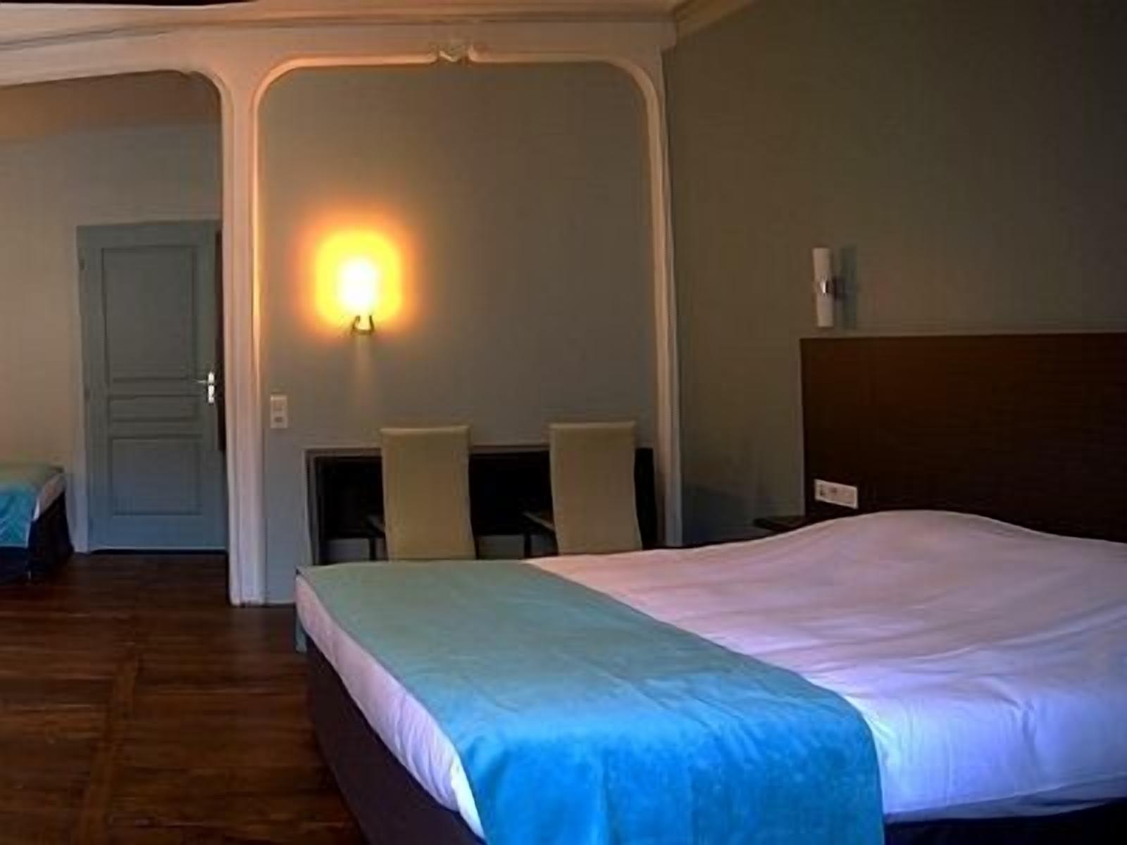 Une chambre d’hôtel avec un lit, un bureau et une chaise.