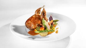 A plate with a roasted duck, vegetables, and sauce.