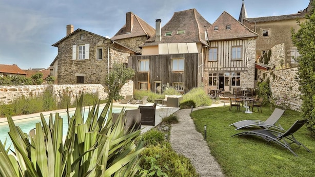 A stone building with a swimming pool, outdoor seating, and a well-maintained garden.