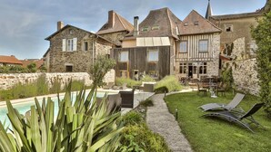 A stone building with a swimming pool, outdoor seating, and a well-maintained garden. - Auberge Dupuytren (Pierre-Buffiere)