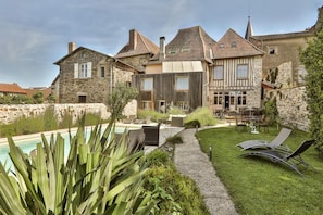A stone building with a swimming pool, outdoor seating, and a well-maintained garden. - Auberge Dupuytren (Pierre-Buffiere)