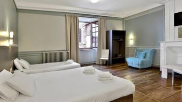 Ein Hotelzimmer mit zwei Betten, einem Sessel, einem Fernseher und einem Kleiderschrank.