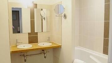 A bathroom with two sinks, a mirror, and a shower area.