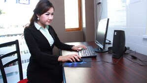 A person working at a desk with a computer, a monitor, and a keyboard. - MK Hotel (Yangon)