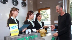 A reception desk with a 'RECEPTION' sign, name tags, and a 'WELCOME' sign. - MK Hotel (Yangon)