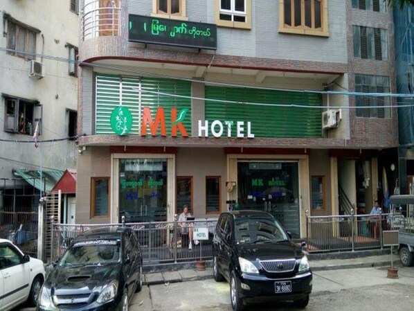 Un hôtel avec un auvent vert et une enseigne sur laquelle on peut lire « HÔTEL MK ».