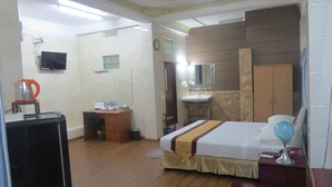 A hotel room with a bed, a desk, a chair, a television, a mirror, and a wardrobe. - MK Hotel (Yangon)