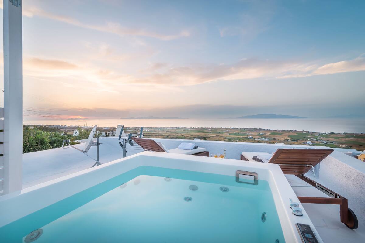 A rooftop pool with a view of the sea and distant land.