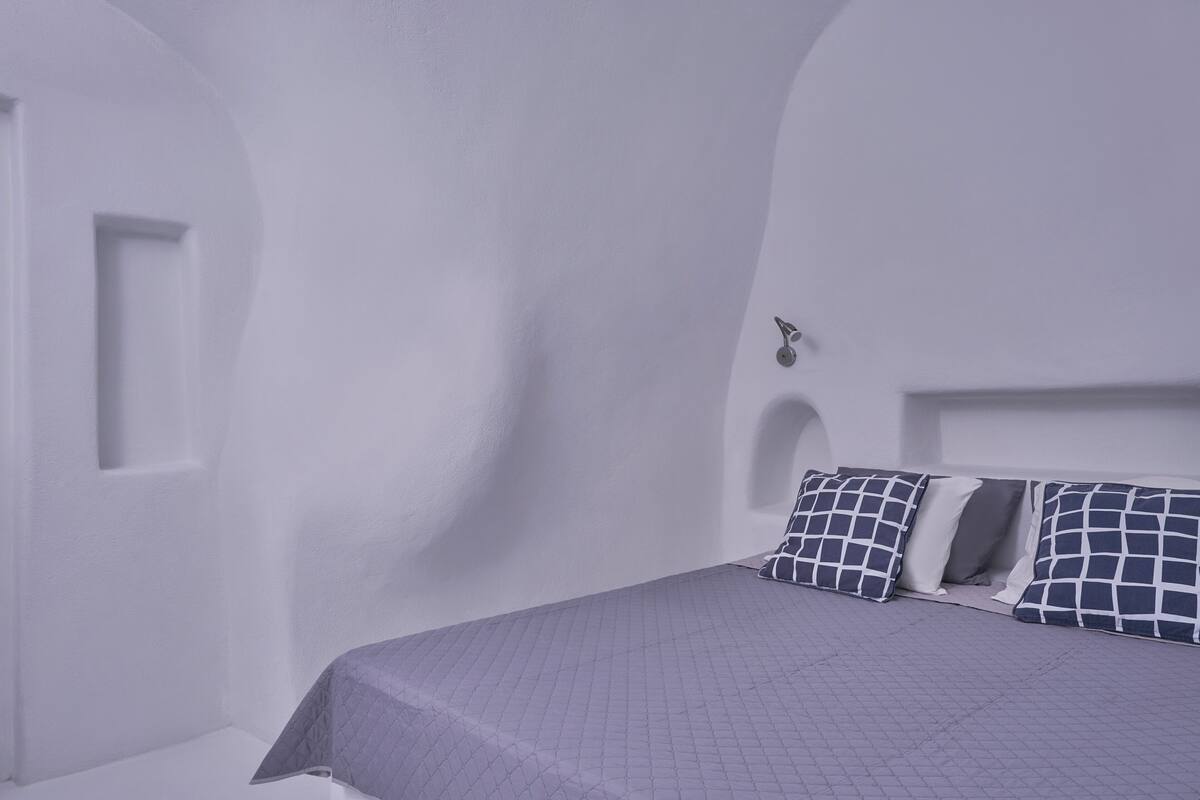 A room with a bed, white walls, and a door.
