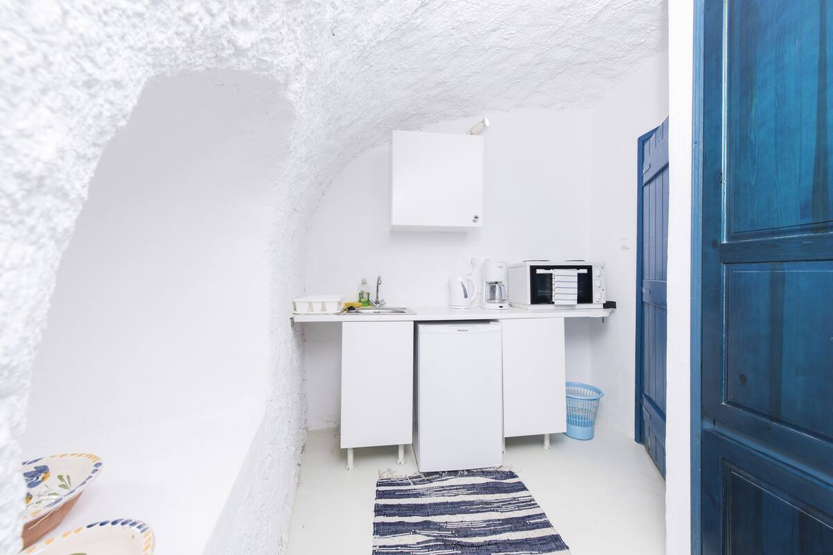 A compact kitchen with white cabinets, a microwave, and a sink.