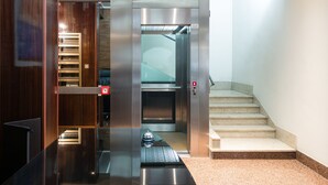 An elevator with a metallic interior, a red emergency button, and a glass door. - Suiteincenter Apartments (Palermo)