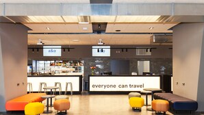 Un vestíbulo moderno con zona de bar, asientos y un gran letrero que dice 'everyone can travel'.