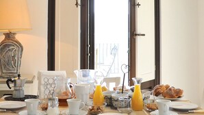 Una mesa de desayuno dispuesta con platos, tazas y una jarras de jugo de naranja.