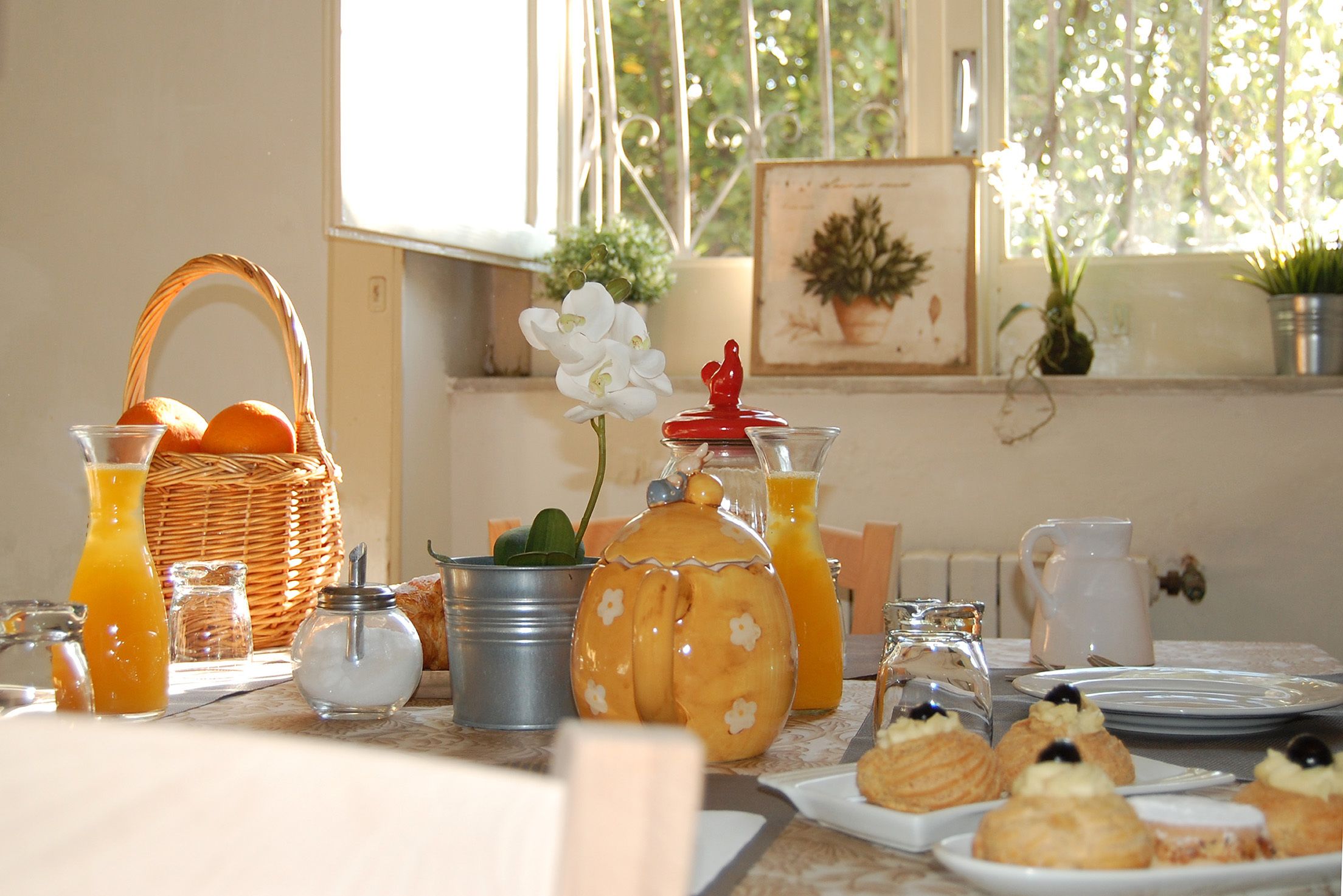 Una mesa de desayuno con jugo de naranja, pastelería y una cesta de mimbre.