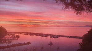 Un puerto deportivo con barcos amarrados, rodeado de aguas tranquilas y un cielo al atardecer.