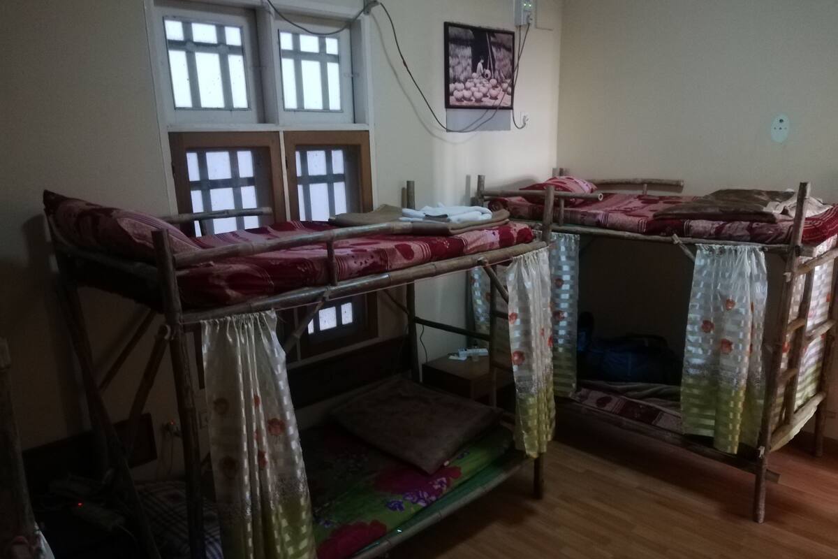 Un dormitorio con literas, una ventana de varios cristales y un enchufe en la pared.