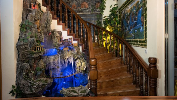 Una escalera de madera con una cascada decorativa y un mural en la pared.