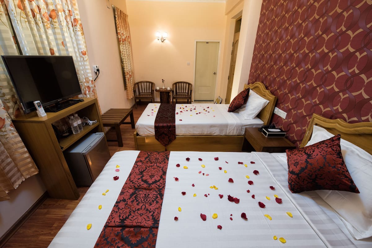 Habitación de hotel con dos camas, televisión, escritorio y una silla.