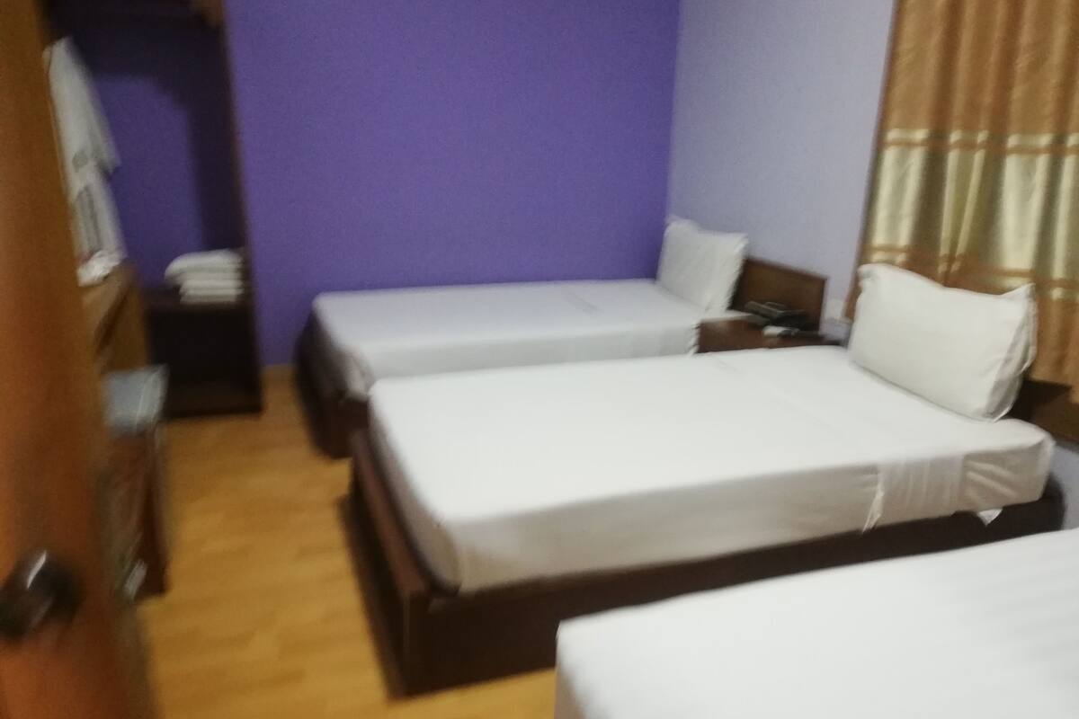 Una habitación con dos camas individuales, un armario de madera y una mesita de noche con una lámpara.