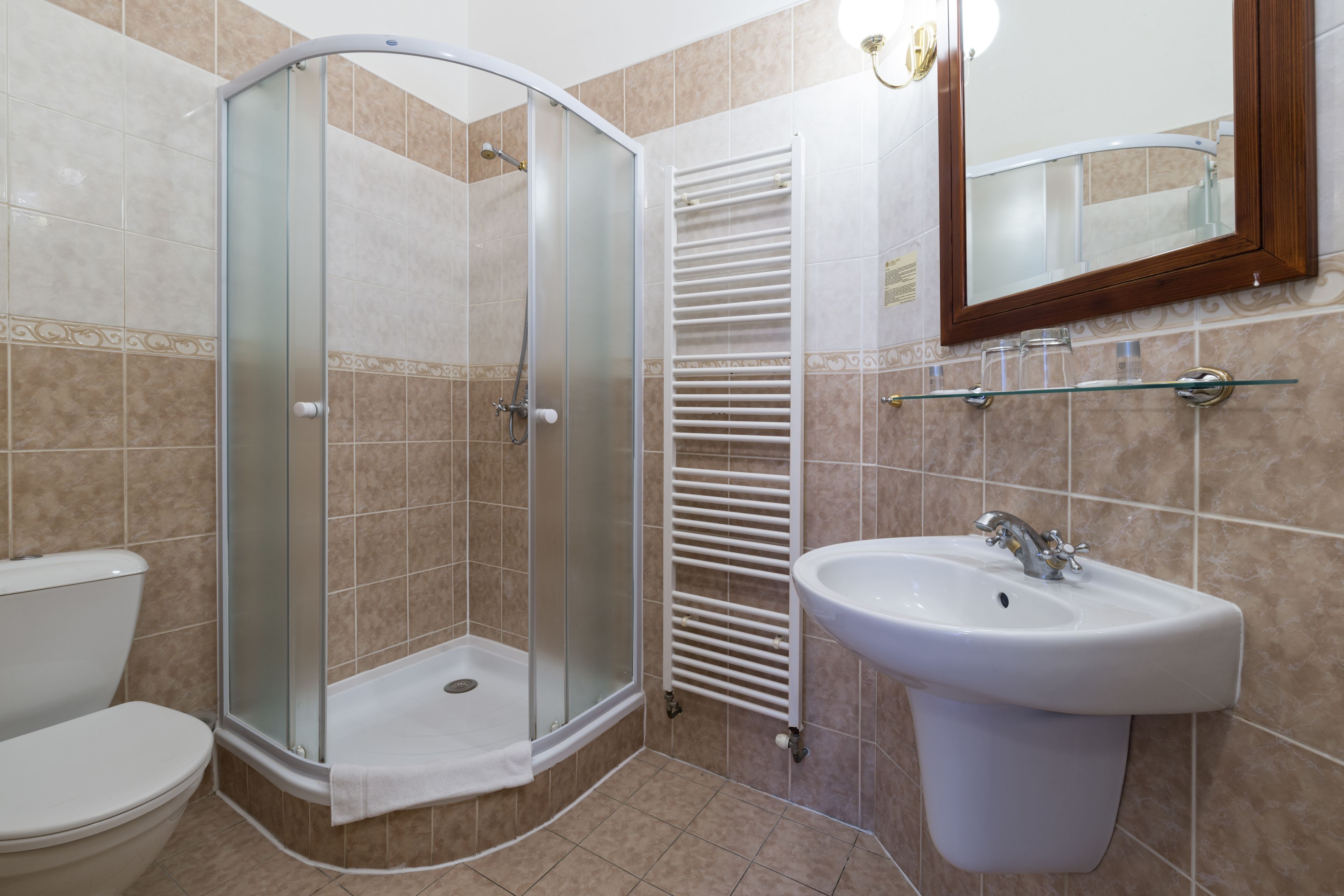 A bathroom with a glass-enclosed shower, a white sink, and a mirror above the sink.