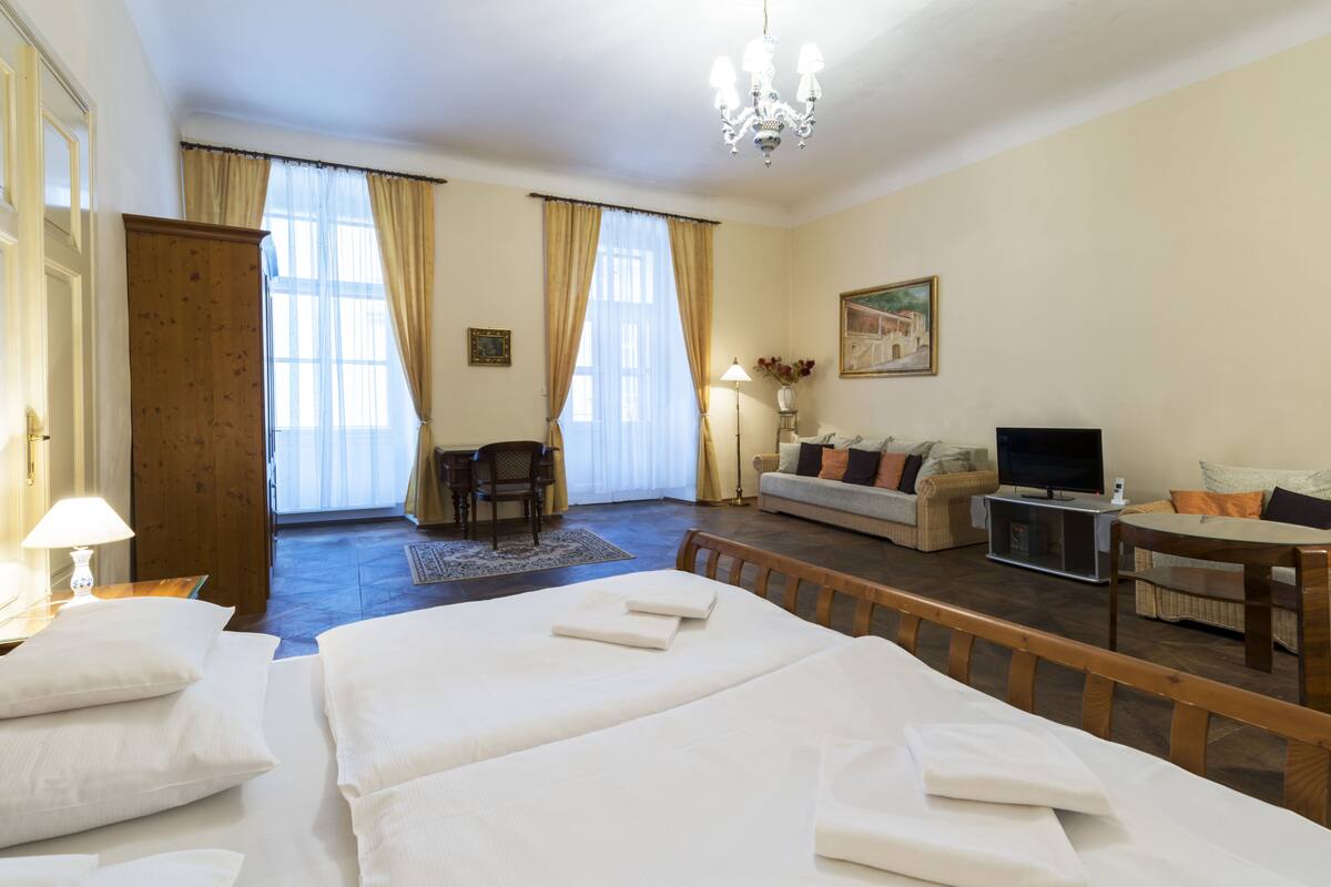 A hotel room with a large bed, a sofa, a TV, and a dining table.