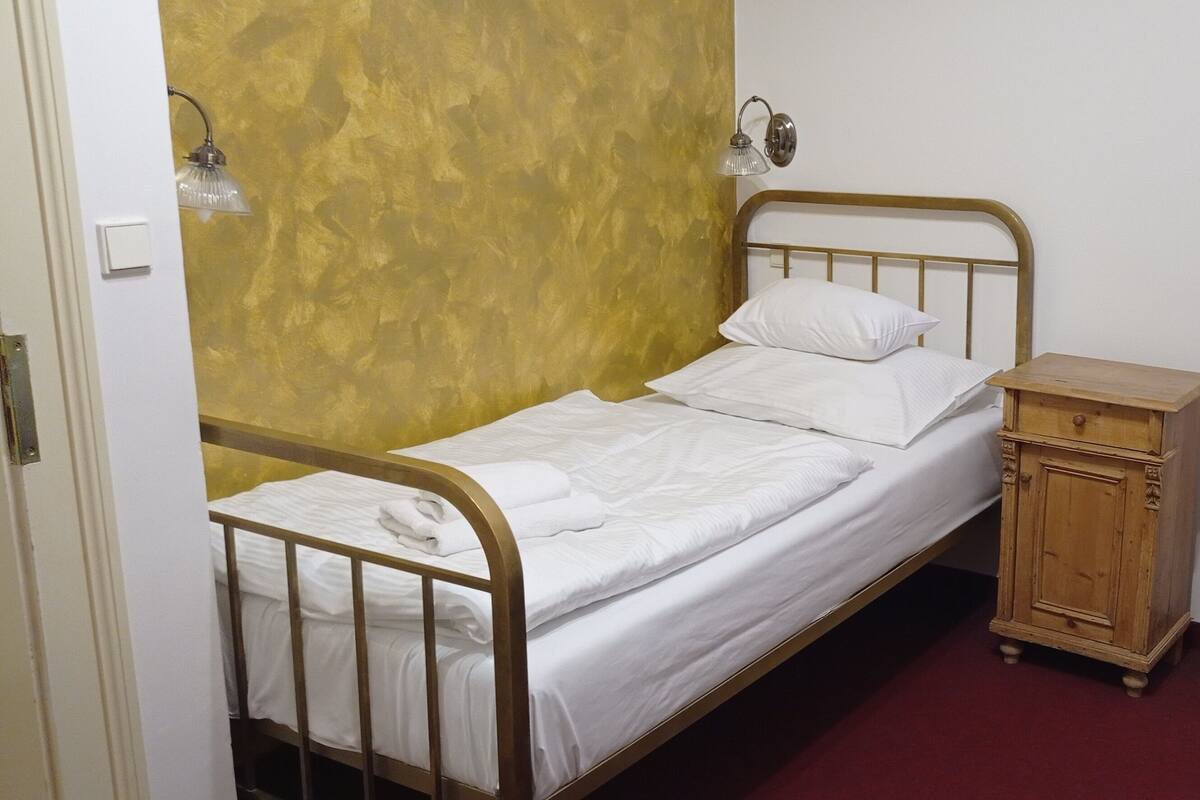 A single bed with a wooden headboard and a nightstand with a drawer.