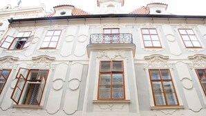 Een gebouw met versierde architecturale details, waaronder decoratieve lijsten en een balkon met een smeedijzeren hekwerk.