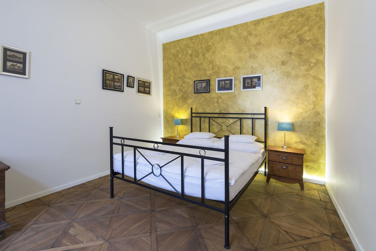 A bedroom with a bed, two bedside tables, and a wall with framed pictures.