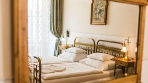 Een bed met hoofdbord, twee nachtkastjes en een spiegel die de kamer weerspiegelt.
