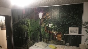 Quarto com cama, mesa de cabeceira, janela e porta.