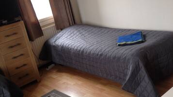 A bedroom with a bed, a dresser, a radiator, and a rug.