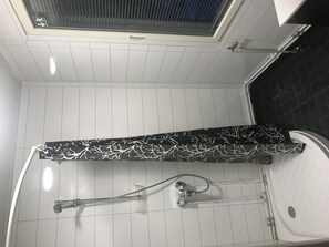 A bathroom with a shower, a towel rack, and a window with blinds. - Hotel Lamminpää (Tampere)