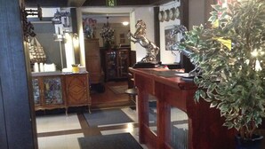 Uma área de recepção com uma mesa de madeira, um vaso de planta e piso ladrilhado.