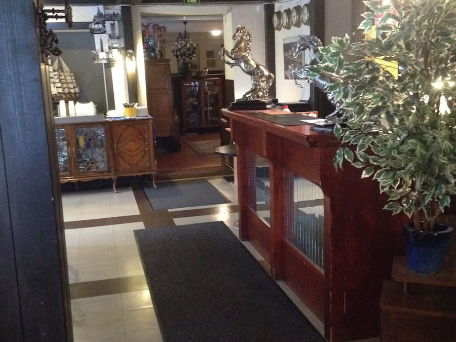 A reception area with a wooden desk, a potted plant, and a tiled floor.