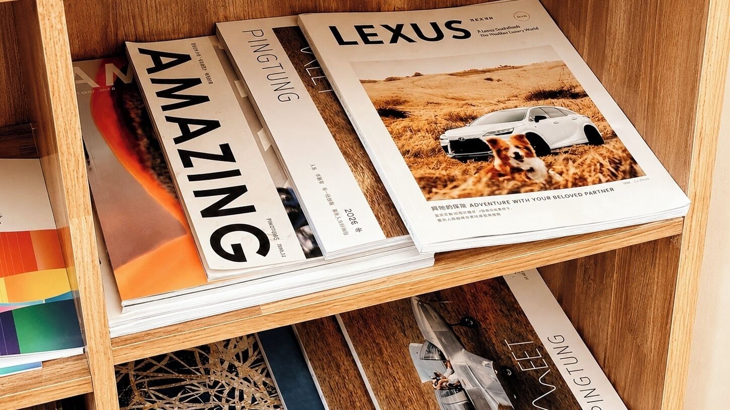 A wooden shelf with magazines, including 'AMAZING' and 'LEXUS.'