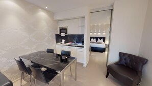 Ein modernes Hotelzimmer mit Essbereich, einer Küchenzeile und einem separaten Schlafzimmer.