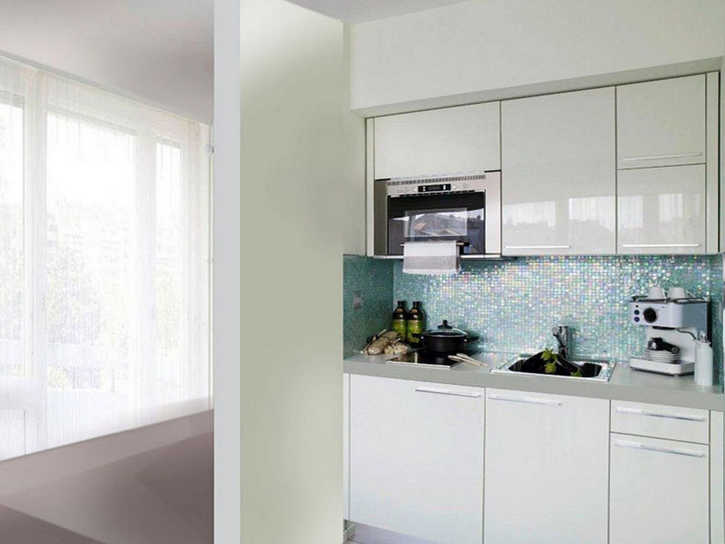 A modern kitchen with white cabinets, a microwave, and a coffee machine.