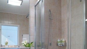 Un baño moderno con ducha envuelta en vidrio, un lavamanos blanco y un espejo sobre él.