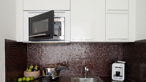 Una cocina equipada con microondas, estufa, lavabo y cafetera.